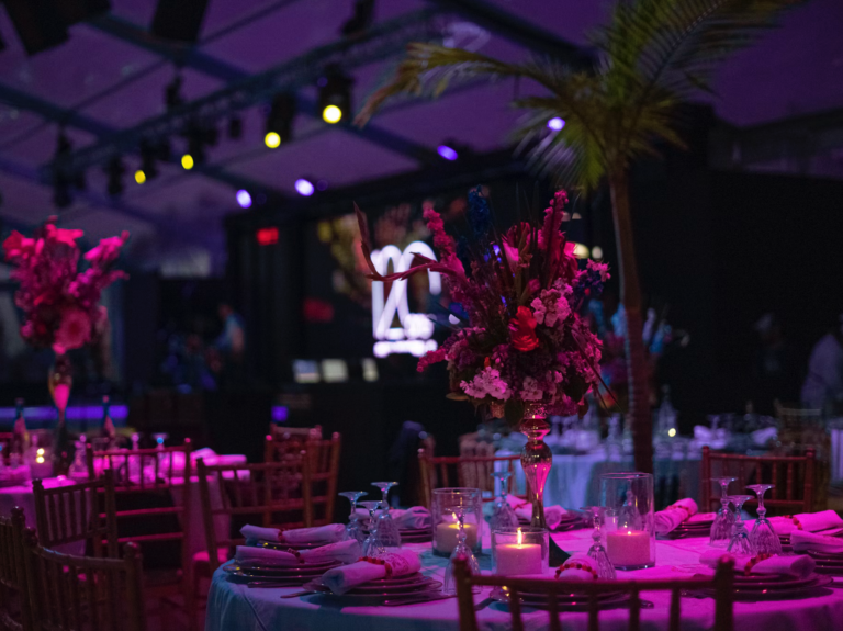 Elegant dukat event med blomsterarrangemang och stämningsfull lila belysning.