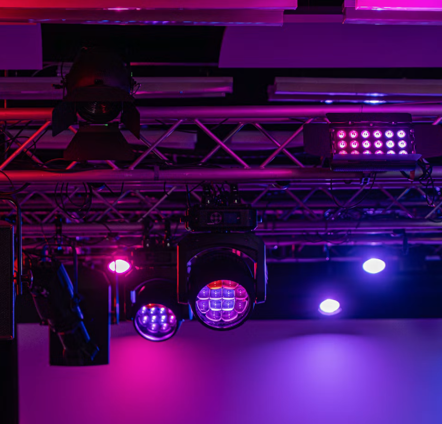Professionell ljusrigg med LED-armaturer och moving heads i rosa och lila belysning.